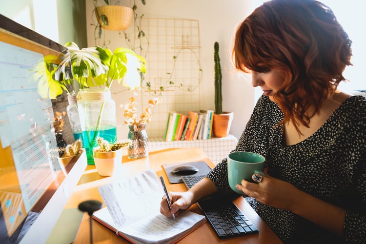Marketer with coffee taking notes in her home office